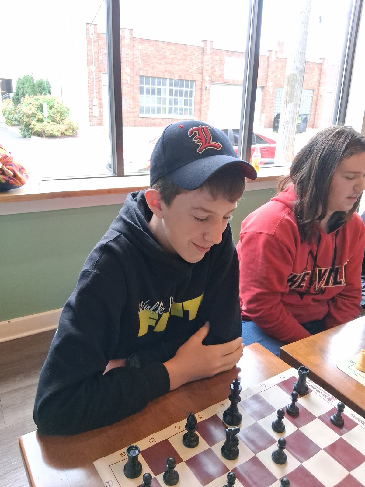 Our tournament winner, smiling in the Louisville cap, youth chess tournament at Locals in Louisville